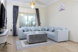 a white living room with a couch and a table at Sea Shore Hotel Apartment Khorfakkan in Khor Fakkan