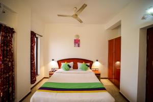 a bedroom with a bed with green and white pillows at Hotel Corbelli in Puducherry