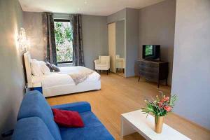 sala de estar con cama y sofá azul en Domaine du Prieuré d'Estagel, en Saint-Gilles