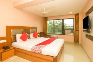 a bedroom with a bed with red pillows and a tv at OYO Hotel Sarovar Grand in Kalamboli