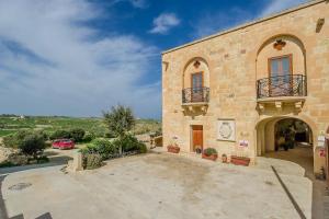 een groot bakstenen gebouw met een klok erop bij Hamlet 1 Holiday Home in Għasri