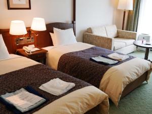 a hotel room with two beds and a couch at Hotel Onikoube in Osaki