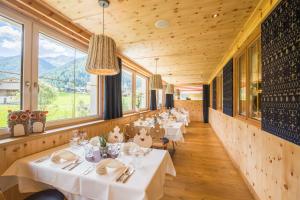 een rij tafels in een restaurant met bergen bij Vitalpina Hotel Magdalenahof in Santa Maddalena in Casies