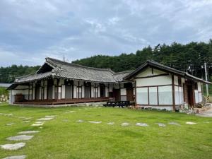a building with a grass yard in front of it at Hakdong Hanok Pension in Gangneung
