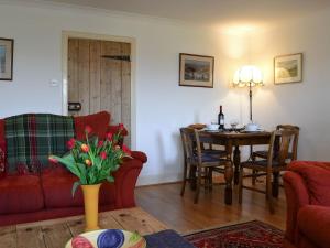 a living room with a red couch and a table at Avenel Cottage in Town Yetholm