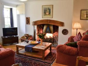 a living room with a table and a fireplace at Avenel Cottage in Town Yetholm