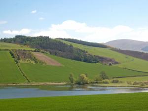a green field with a lake in the middle at Avenel Cottage in Town Yetholm