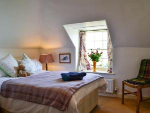 a bedroom with a bed with a teddy bear on it at Avenel Cottage in Town Yetholm