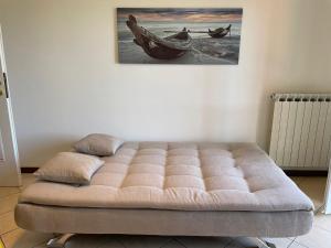 un letto a trapuntamento in una stanza con un dipinto sul muro di Appartamento Note d’estate a Marina dʼAndora