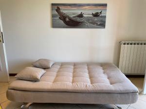 a tufted bed in a room with a painting on the wall at Appartamento Note d’estate in Marina dʼAndora +3 photos