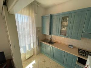 une cuisine avec des placards bleus, un évier et une fenêtre dans l'établissement Appartamento Note d’estate, à Marina dʼAndora