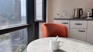 una tazza di caffè bianco appoggiata su un tavolo davanti a una finestra di HostelOne a Ulaanbaatar