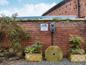 a brick wall with a parking meter next to two plants at Sparrow - Uk30747 in Acton Trussell