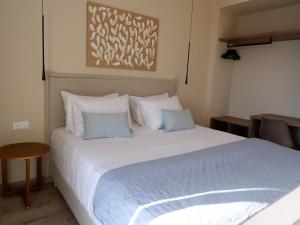 una camera da letto con un grande letto bianco con cuscini blu di Kaiser Luxury Suites ad Achílleion