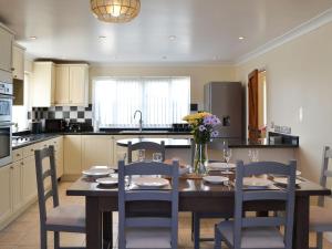 a kitchen with a wooden table and chairs and a kitchen with a table and chairs at Teasel in Stalham