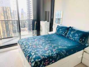 a bedroom with a bed with blue sheets and a window at Melbourne CBD Empire Apartment in Melbourne