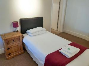 a small bedroom with a white bed and a night stand at The Dolphin - Uk31004 in Avoch