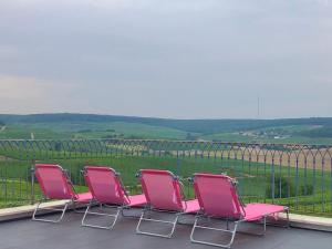 un grupo de sillas rosas sentadas en un balcón en FLORESSENS EN CHAMPAGNE Terrasse privative sur le vignoble, en Fleury-la-Rivière