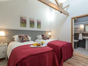 a bedroom with two beds with red sheets and a tray of food at Daisy in Scruton