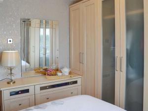 a bedroom with a dresser with a mirror and a bed at Honeysuckle Cottage in Springside