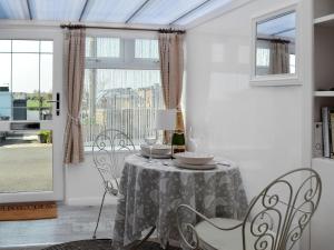 a dining room with a table and chairs and a window at Honeysuckle Cottage in Springside