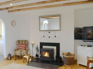 a living room with a fireplace and a tv at Honeysuckle Cottage in Springside