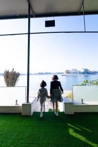 An NāmīにあるGrande Beachの水辺を見渡すバルコニーを歩く女性と子供 +5枚の写真