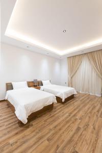two beds in a white room with wooden floors at Grande Beach in An Nāmī