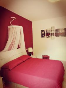 sypialnia z czerwono-białym łóżkiem z baldachimem w obiekcie La Casa di Golia w mieście Bagni San Filippo