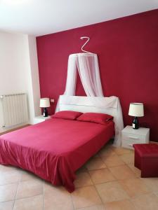 a bedroom with a bed with a red wall at La Casa di Golia in Bagni San Filippo