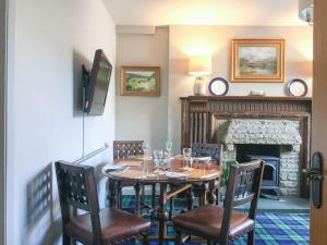 a dining room with a table and chairs and a fireplace at Shambles Cottage in Ambleside
