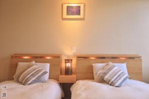 duas camas com almofadas brancas sentadas uma ao lado da outra em 山の源-Yama No Minamoto em Furano