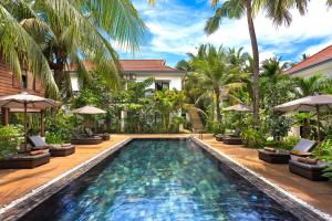 a swimming pool in front of a house with palm trees at Apsara Greenland Boutique Villa & Resort in Siem Reap