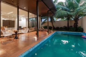 a swimming pool with chairs and a table in a house at StayVista at Bella Orion with Pvt Pool- North Goa in Calangute