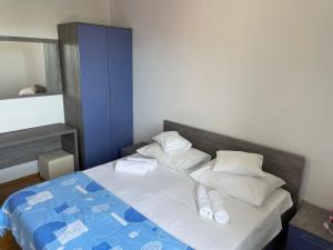 a bed with white pillows and a blue blanket at Apartments Dumina in Murter