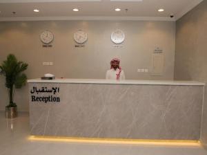 a woman standing behind a counter with clocks on the wall at شقق الراحه للشقق المخدومة in Jeddah