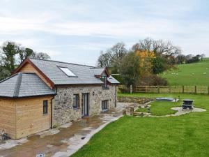 una casa de piedra con techo solar y patio en Bluebell Barn, en Okehampton
