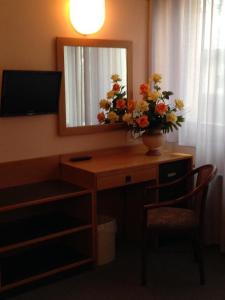 a desk with a mirror and a vase with flowers on it at Hotel Villa Reale in Argenta