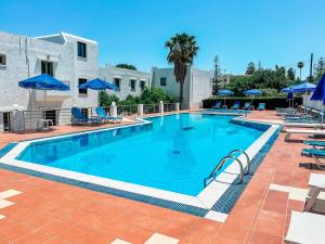 een zwembad met stoelen en blauwe parasols bij Dimitra Hotel in Chersonissos