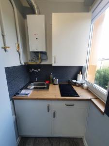 uma cozinha com armários brancos, um lavatório e uma janela em Forest House em Dębica