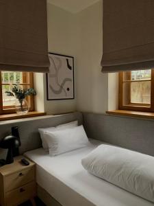 a bedroom with a white bed with two windows at Bob W Peterhof in Freising