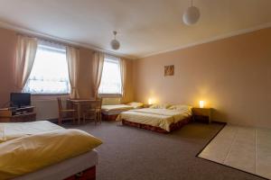 a bedroom with two beds and a desk and a television at Hotel Koruna in Roudnice nad Labem