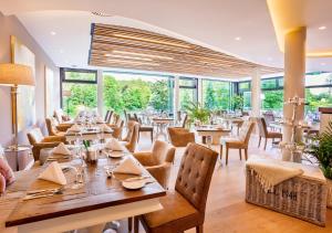 um restaurante com mesas, cadeiras e janelas em Romantischer Winkel RoLigio & Wellness Resort em Bad Sachsa