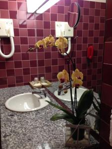 a bathroom with a sink and a vase with yellow flowers at Hotel Villa Reale in Argenta
