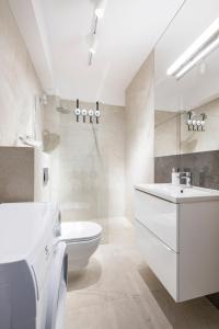 a white bathroom with a sink and a toilet at Apartament Natural 306 z widokiem na morze in Darłówko