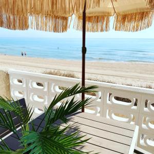 una sombrilla de paja con vistas a la playa en Modern beachfront townhouse, en El Perelló