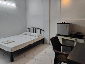 una piccola camera con letto e piccolo frigorifero di Mysore Studio Rooms a Mysore