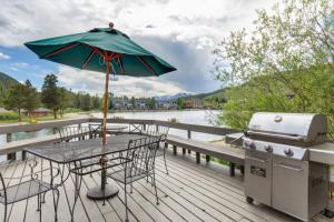 a table with an umbrella and a grill on a deck at Lakeshore by Summit County Mountain Retreats in Keystone