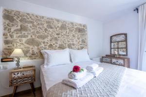 a bedroom with a bed with towels and a stone wall at Pool Villa Michail, in Kissamos! in Koukounará