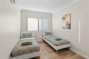 a bedroom with two beds and a window at 136 Madaffari Drive in Exmouth